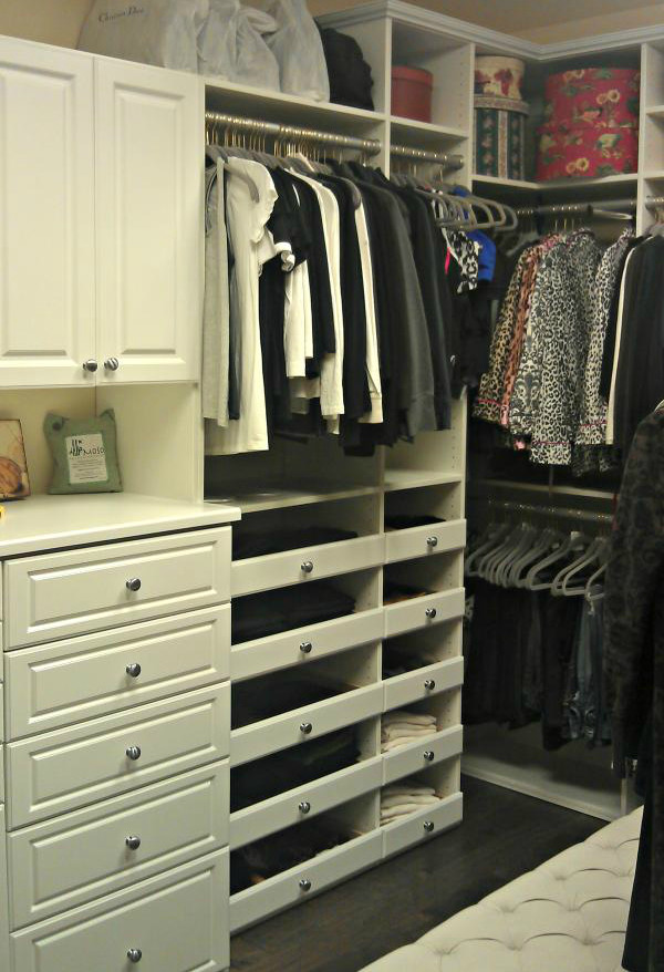 Diseño de armario vestidor unisex clásico grande con armarios con paneles con relieve, puertas de armario blancas, suelo de madera oscura y suelo gris