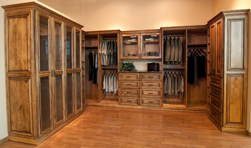 Modelo de armario vestidor de hombre rústico grande con armarios con rebordes decorativos, puertas de armario de madera oscura y suelo de madera en tonos medios