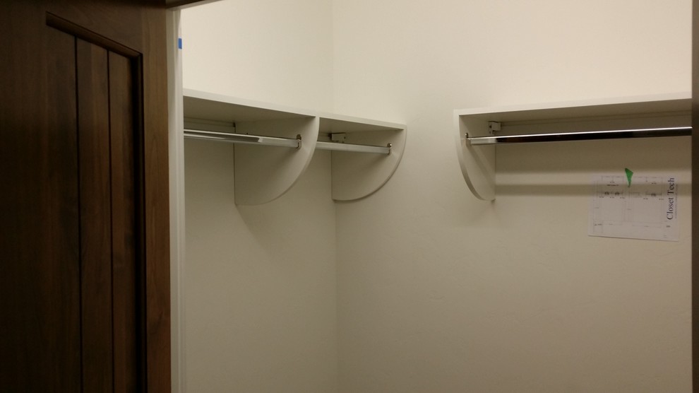 Cette photo montre un petit placard dressing tendance neutre avec un placard sans porte et des portes de placard blanches.