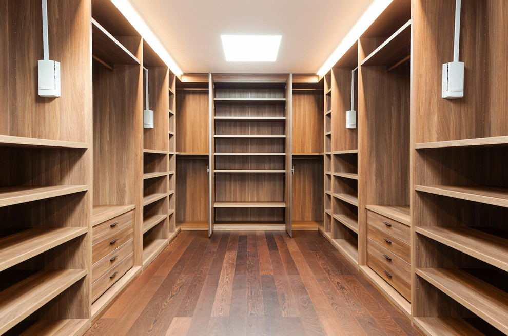 Imagen de armario vestidor unisex de estilo americano grande con puertas de armario de madera clara, suelo de madera oscura, suelo marrón y armarios abiertos