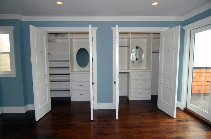 Foto de armario vestidor unisex clásico renovado de tamaño medio con armarios con paneles lisos, puertas de armario blancas y suelo de madera oscura