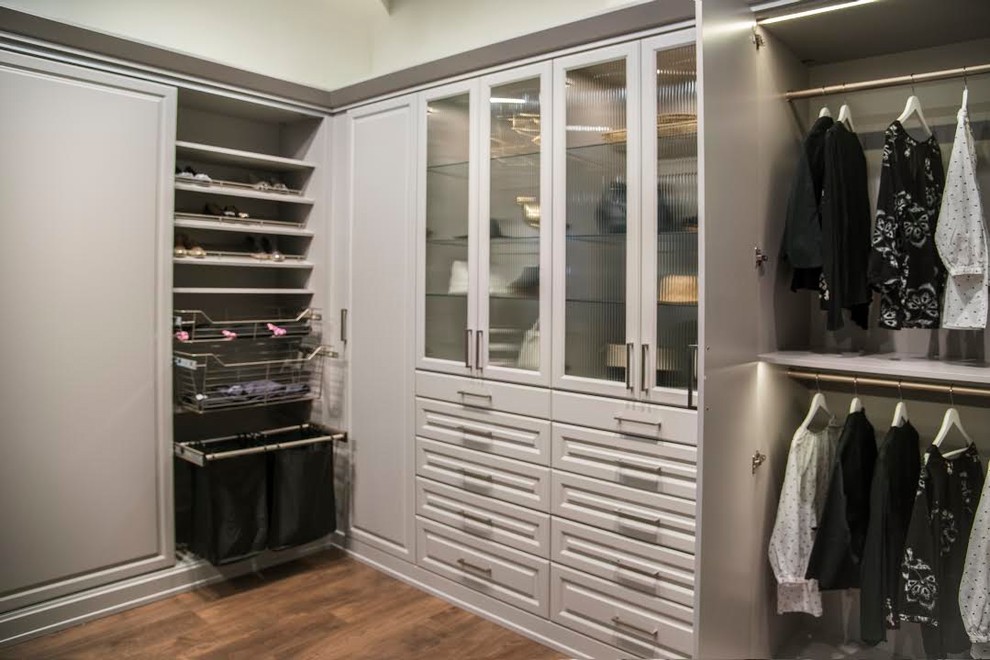 Ejemplo de armario vestidor de mujer clásico renovado grande con armarios con paneles con relieve, puertas de armario blancas, suelo de madera oscura y suelo marrón