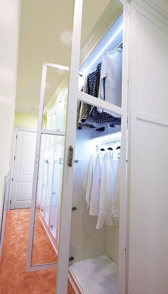 Cette photo montre un très grand dressing room chic avec un placard à porte vitrée, des portes de placard blanches, moquette et un sol marron.