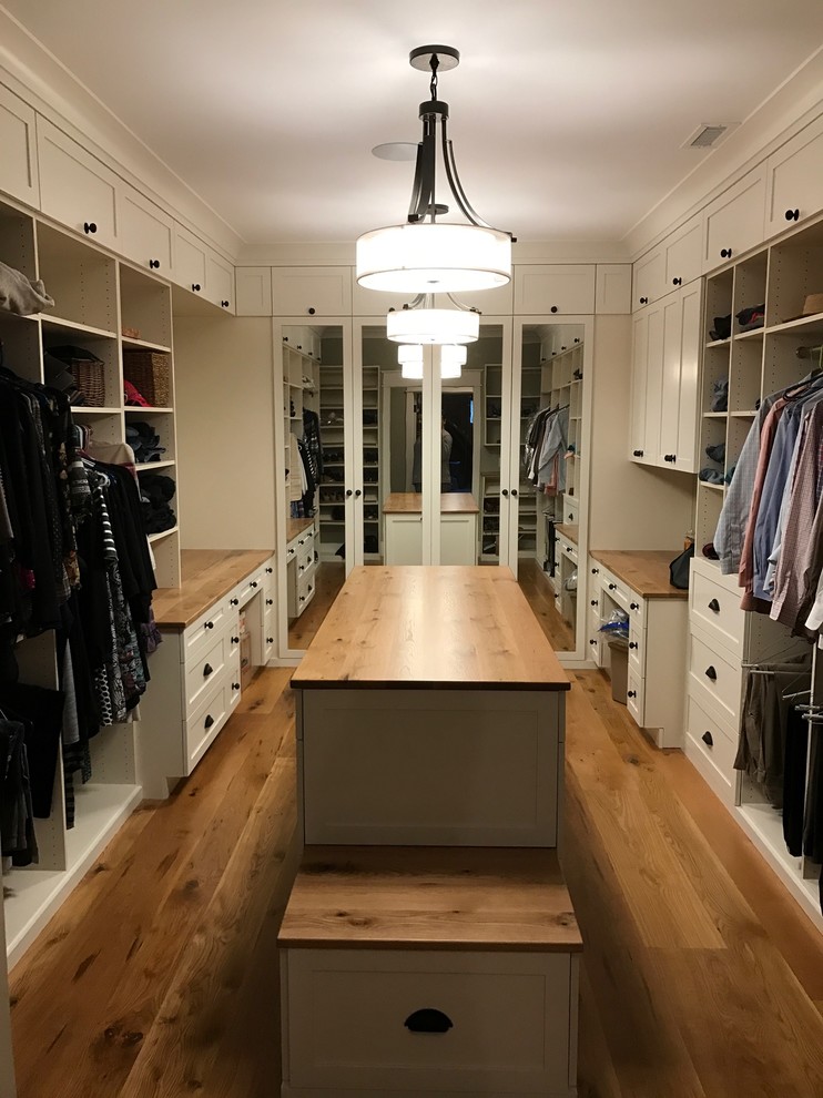 Diseño de armario vestidor unisex campestre con armarios estilo shaker, puertas de armario blancas y suelo de madera en tonos medios