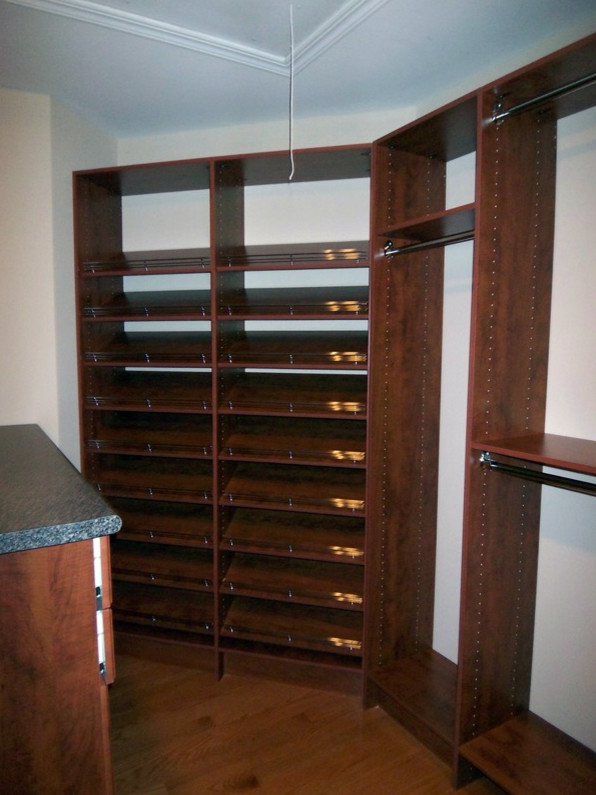 This is an example of a large classic gender neutral walk-in wardrobe in DC Metro with raised-panel cabinets, medium wood cabinets and medium hardwood flooring.
