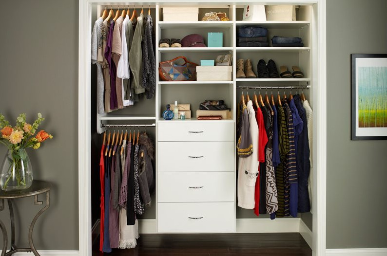 Diseño de armario unisex tradicional renovado pequeño con armarios con paneles lisos, puertas de armario blancas, suelo de madera oscura y suelo marrón
