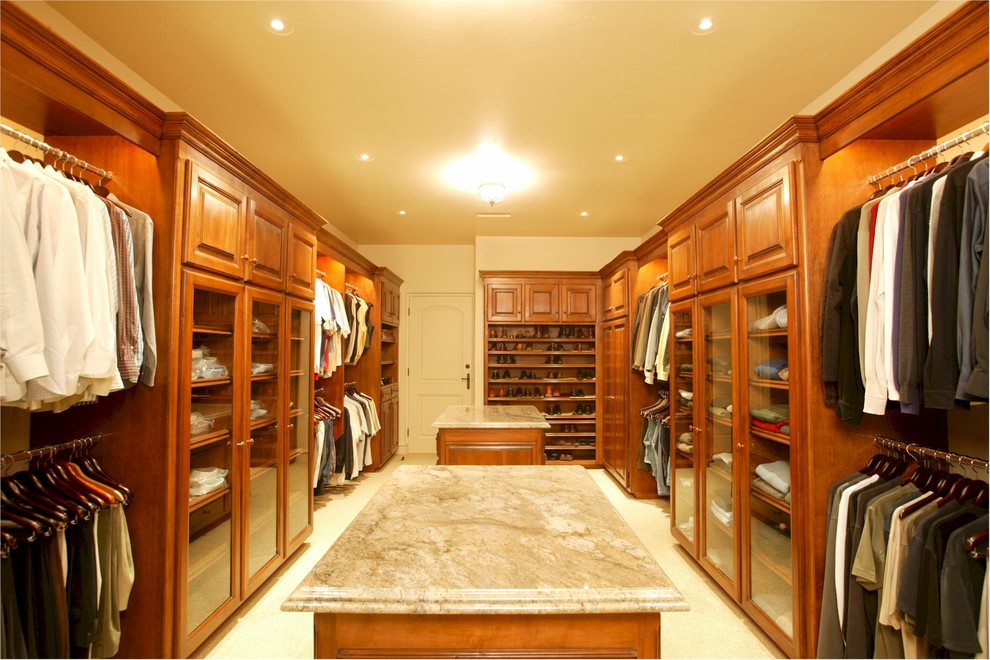 Ejemplo de armario vestidor de hombre de estilo americano grande con armarios con paneles con relieve, puertas de armario de madera oscura y suelo de baldosas de cerámica