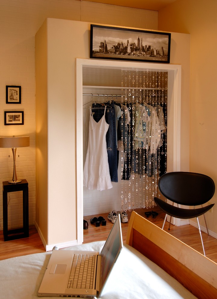 Cette image montre un petit dressing design neutre avec des portes de placard blanches, parquet clair et des rideaux.
