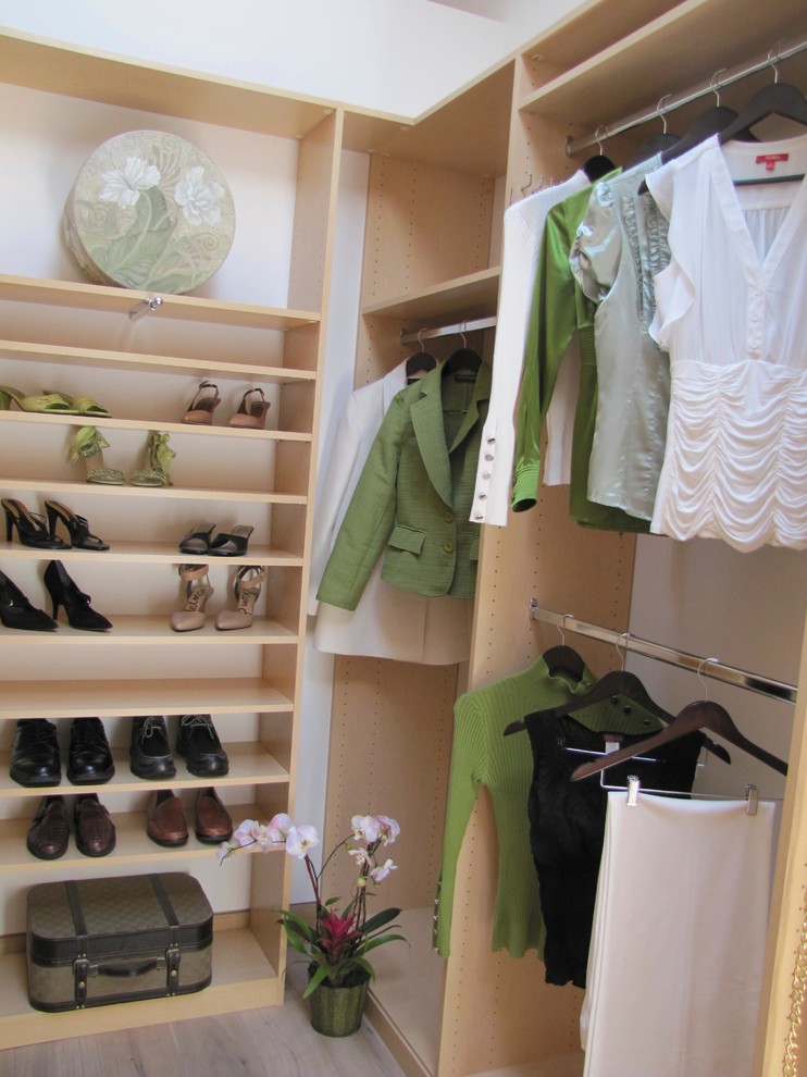 Modelo de armario vestidor unisex contemporáneo de tamaño medio con armarios abiertos, puertas de armario de madera clara y suelo de madera en tonos medios