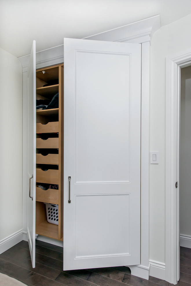 Diseño de armario unisex tradicional renovado de tamaño medio con armarios con paneles empotrados, puertas de armario blancas y suelo de madera oscura