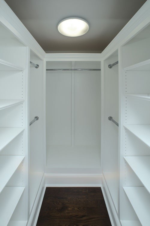 Inspiration pour un dressing room traditionnel de taille moyenne et neutre avec un placard avec porte à panneau surélevé, des portes de placard blanches et parquet foncé.