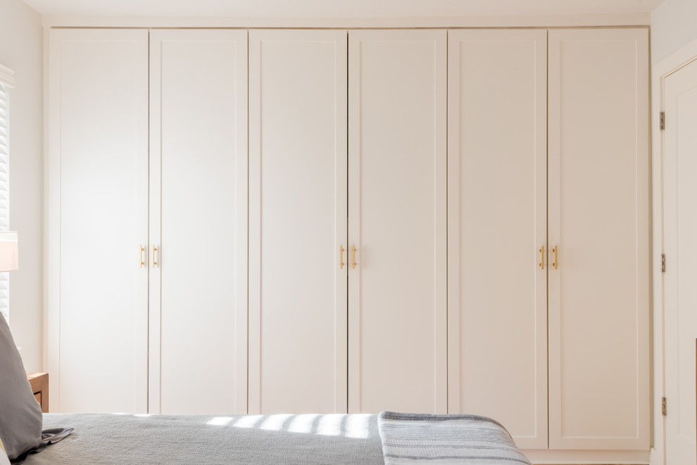 Photo of a medium sized contemporary gender neutral standard wardrobe in Houston with flat-panel cabinets and white cabinets.