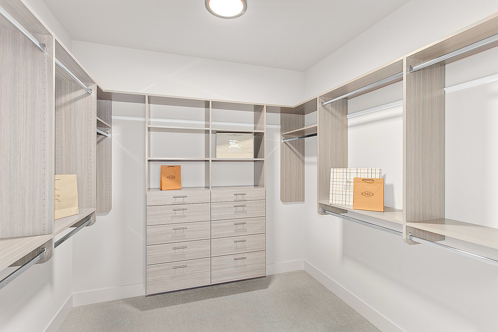 Example of a large trendy gender-neutral carpeted and beige floor walk-in closet design in Seattle with flat-panel cabinets and light wood cabinets