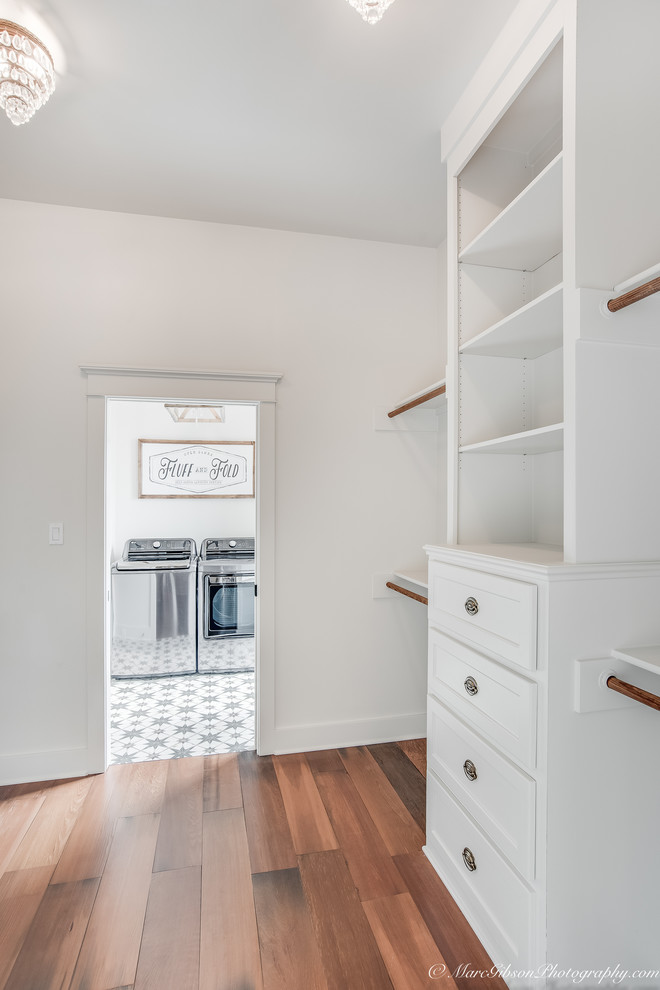 Walk-in closet - mid-sized cottage gender-neutral medium tone wood floor and brown floor walk-in closet idea in New Orleans with shaker cabinets and white cabinets