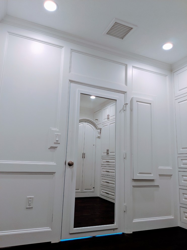 На фото: большая гардеробная комната унисекс в стиле модернизм с фасадами с выступающей филенкой, белыми фасадами, темным паркетным полом, коричневым полом и сводчатым потолком