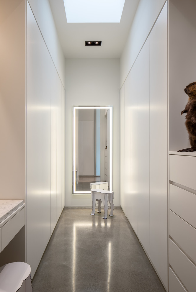 Inspiration for a modern gender neutral dressing room in Seattle with flat-panel cabinets, white cabinets, concrete flooring and grey floors.