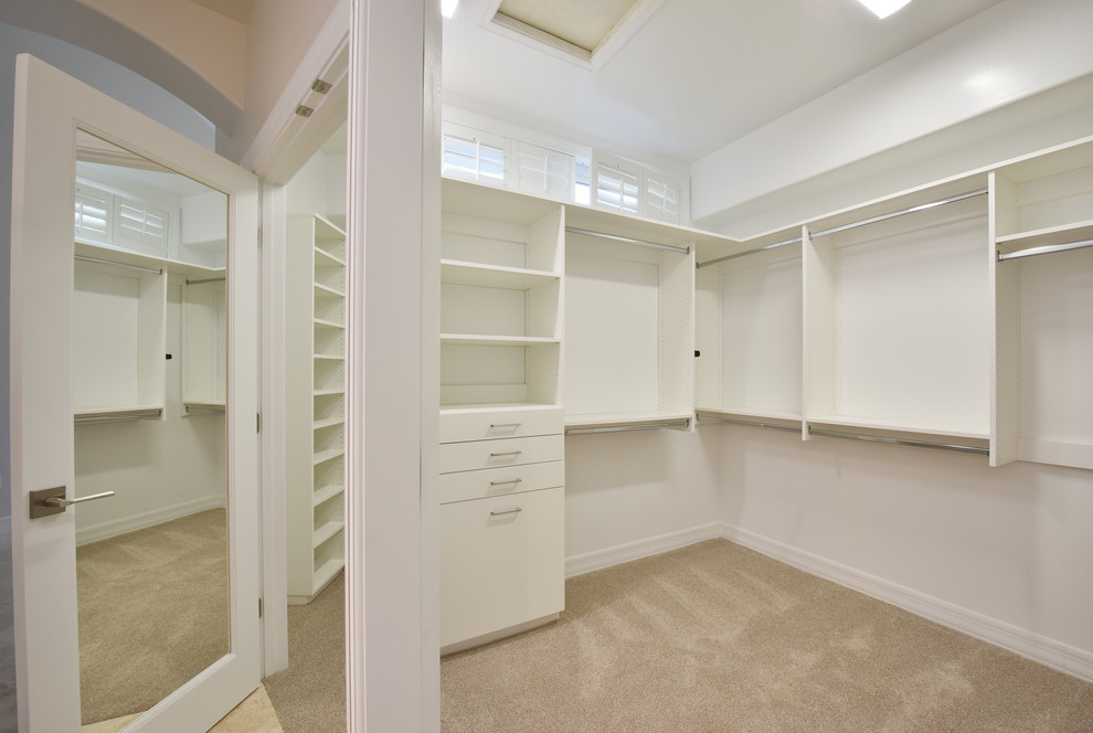 Foto de armario vestidor unisex actual de tamaño medio con armarios abiertos, puertas de armario blancas, moqueta y suelo beige