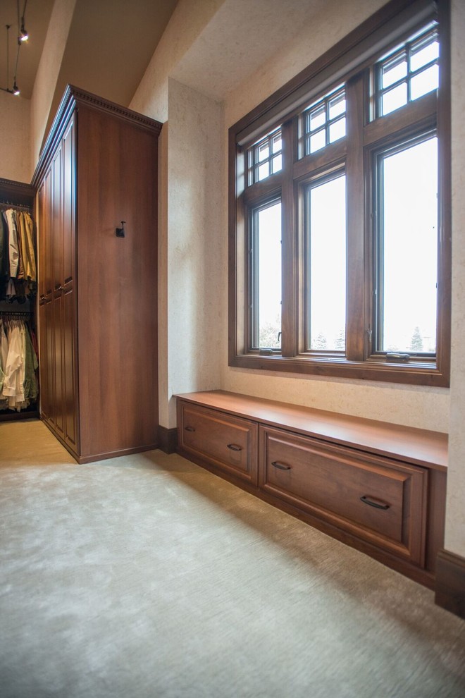 Inredning av ett klassiskt mellanstort walk-in-closet för könsneutrala, med luckor med upphöjd panel, skåp i mellenmörkt trä, heltäckningsmatta och beiget golv
