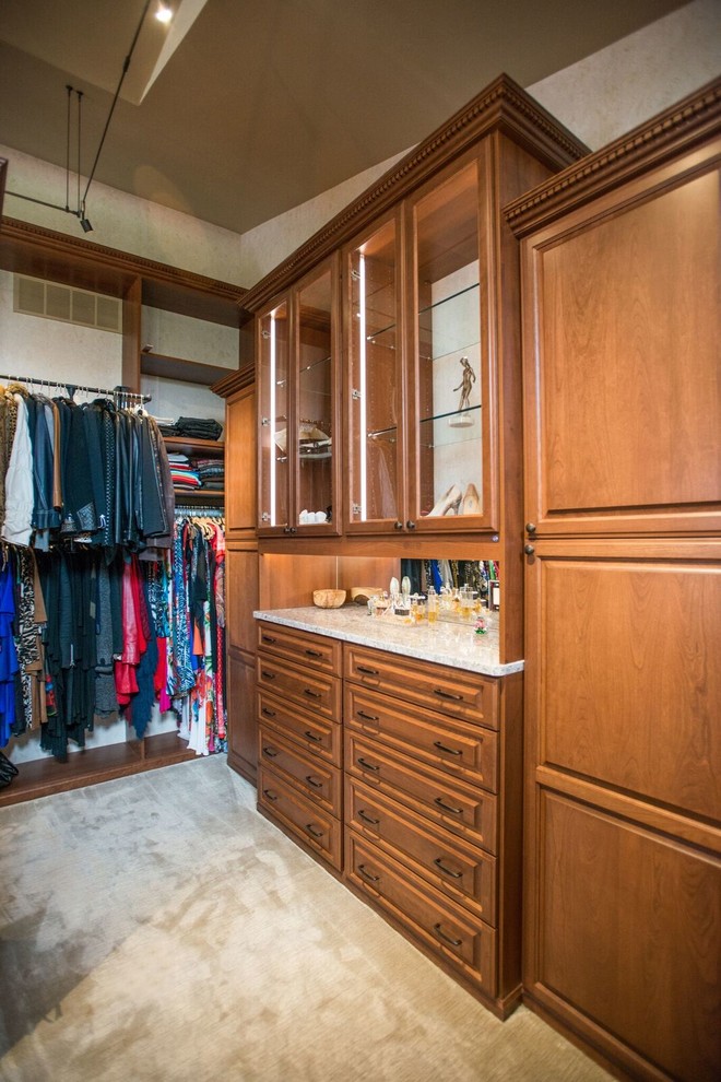 Diseño de armario vestidor unisex tradicional de tamaño medio con armarios con paneles con relieve, puertas de armario de madera oscura, moqueta y suelo beige
