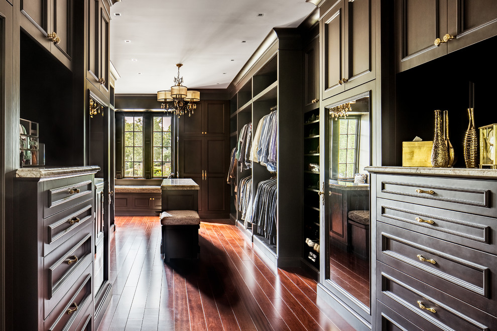 Photo of a large traditional walk-in wardrobe for men in New York with dark wood cabinets, recessed-panel cabinets and medium hardwood flooring.