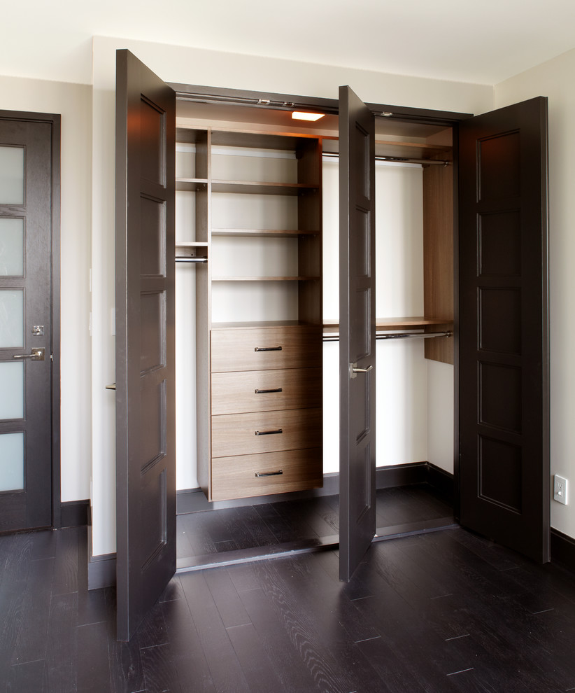 Diseño de armario unisex contemporáneo de tamaño medio con armarios con paneles lisos, puertas de armario de madera clara y suelo de madera oscura