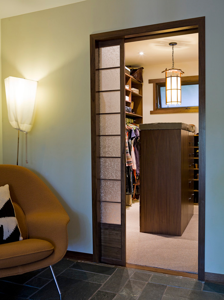 This is an example of a small contemporary gender neutral walk-in wardrobe in Los Angeles with open cabinets, dark wood cabinets and carpet.