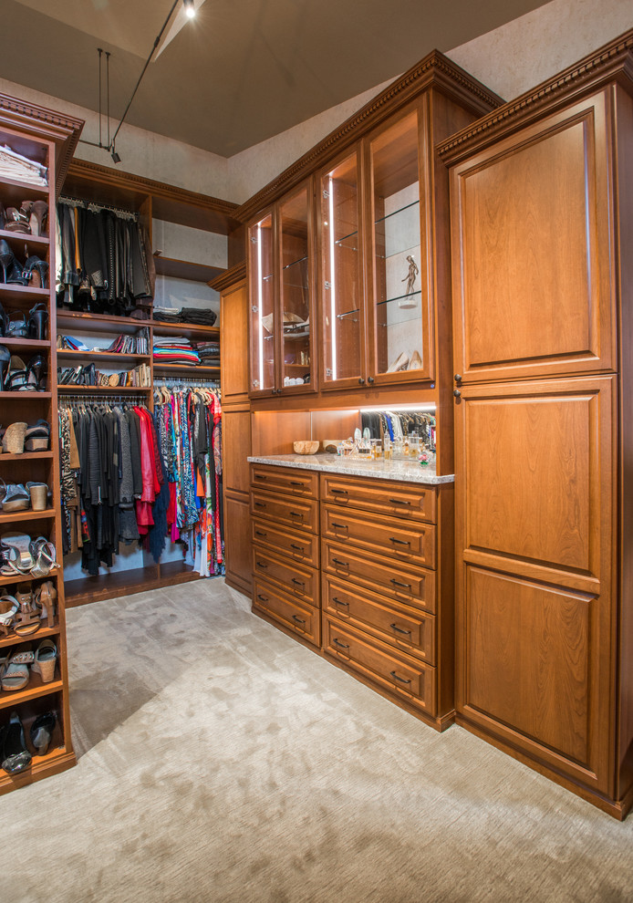 Walk-in closet - huge traditional gender-neutral carpeted and beige floor walk-in closet idea in Denver with raised-panel cabinets and medium tone wood cabinets