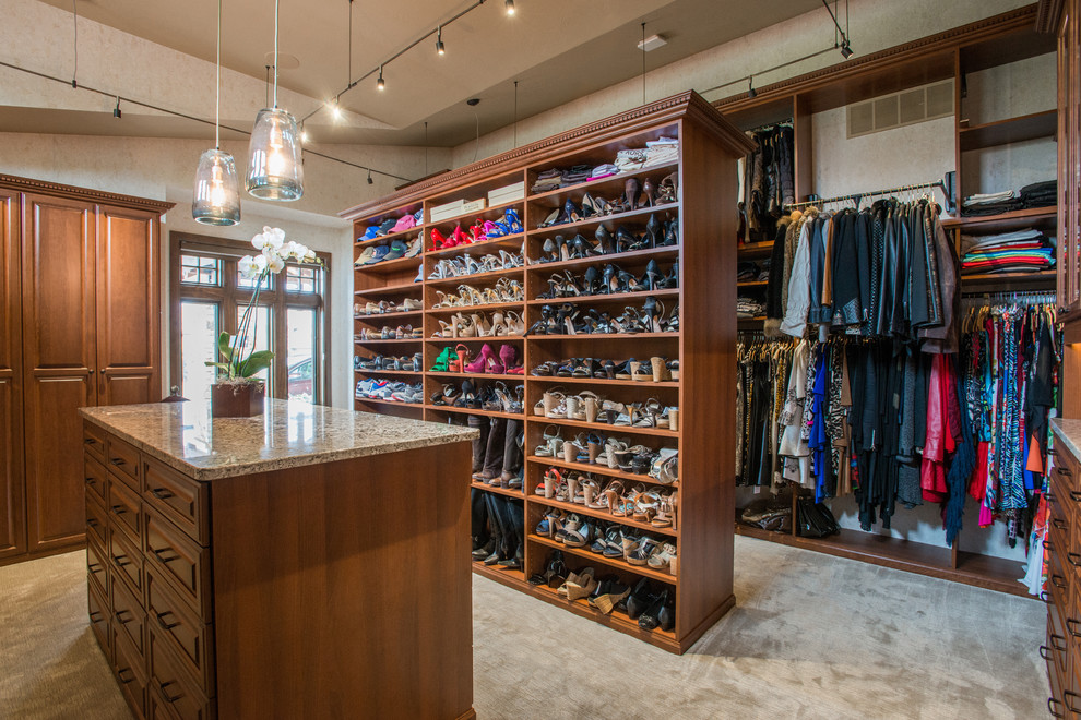 Photo of an expansive traditional gender neutral walk-in wardrobe in Denver with raised-panel cabinets, medium wood cabinets, carpet and beige floors.