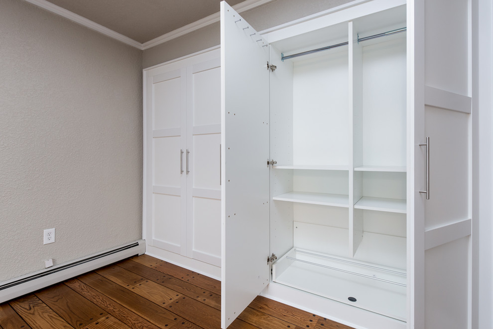 Foto di un piccolo armadio o armadio a muro classico con ante lisce, ante bianche e pavimento in legno massello medio