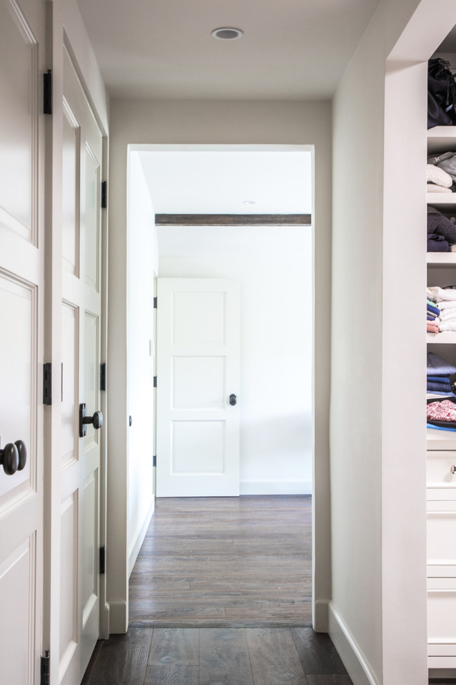 Foto de armario y vestidor unisex tradicional renovado con armarios con paneles empotrados, puertas de armario blancas y suelo de madera oscura