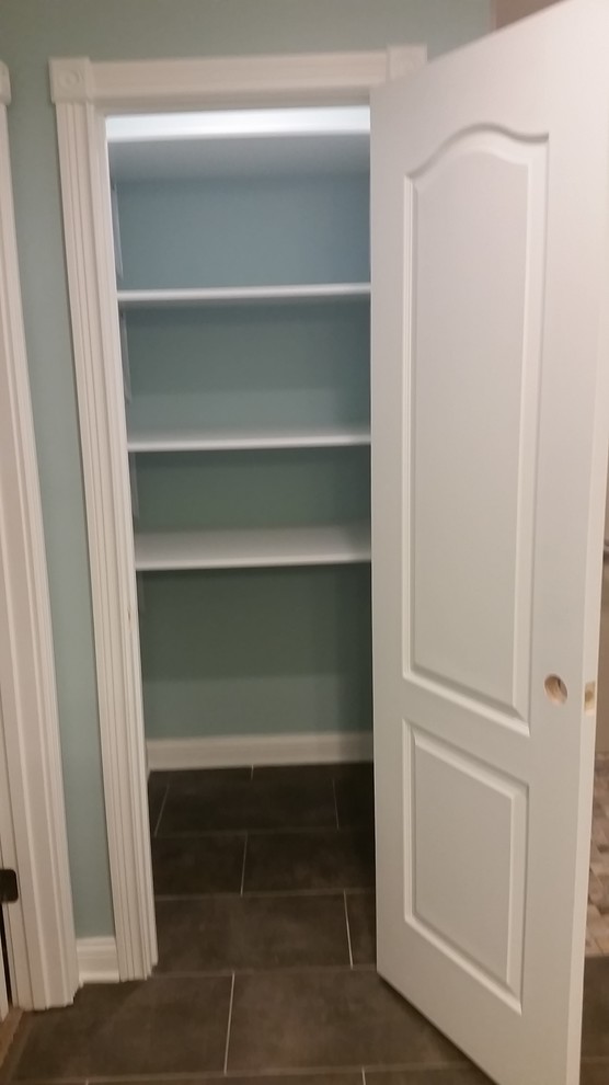 Photo of a small contemporary gender neutral standard wardrobe in Indianapolis with flat-panel cabinets, white cabinets and porcelain flooring.