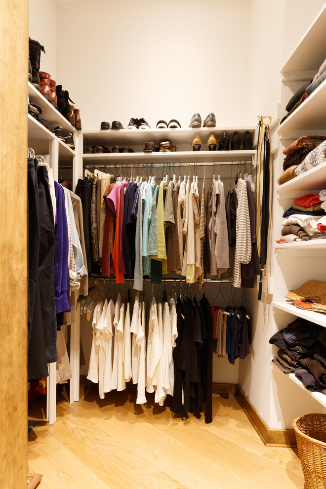 Diseño de armario vestidor unisex contemporáneo de tamaño medio con armarios abiertos, puertas de armario blancas, suelo de madera clara y suelo beige