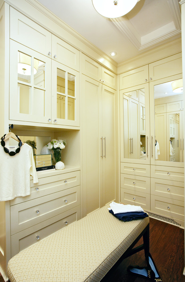 Cette image montre un dressing room design pour une femme avec des portes de placard beiges, parquet foncé et un placard à porte shaker.