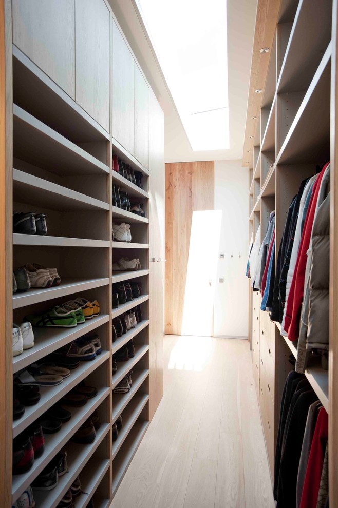 Trendy walk-in closet photo in New York with light wood cabinets