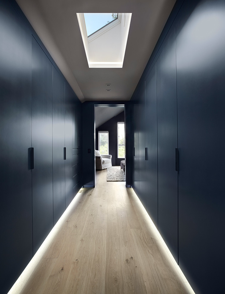 Стильный дизайн: большая гардеробная комната в современном стиле с плоскими фасадами, синими фасадами и светлым паркетным полом - последний тренд