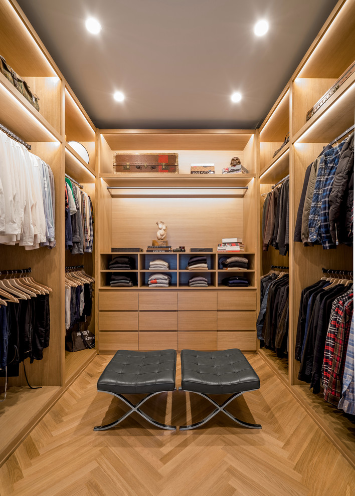 Inspiration for a contemporary walk-in wardrobe for men in Los Angeles with open cabinets, light wood cabinets, light hardwood flooring and feature lighting.