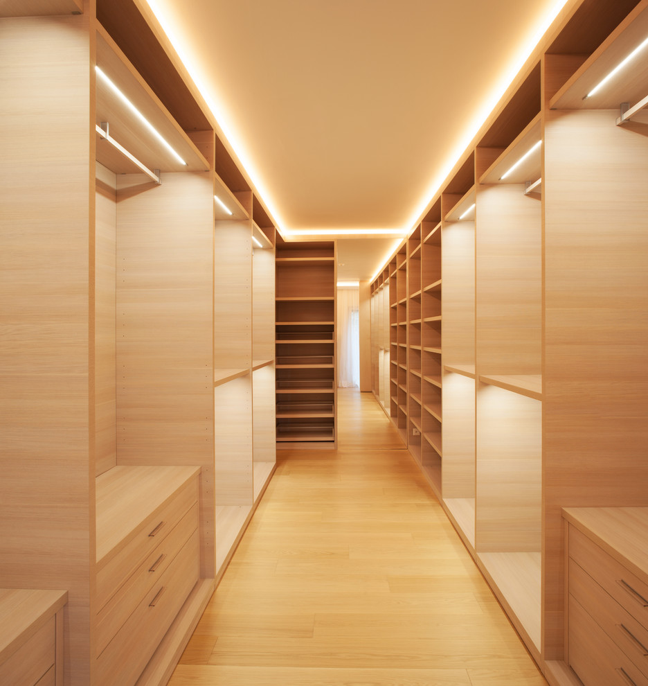 Imagen de vestidor unisex actual grande con armarios con paneles lisos, puertas de armario de madera clara, suelo de madera clara y suelo marrón