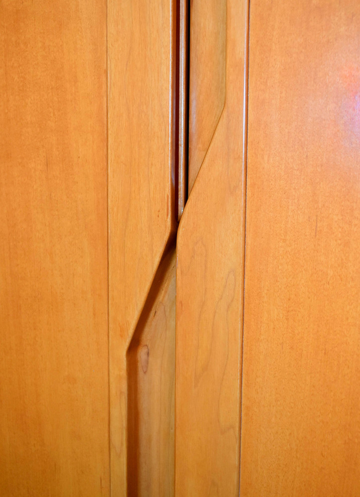 Diseño de armario unisex actual pequeño con armarios con paneles lisos, puertas de armario de madera clara y suelo de madera clara