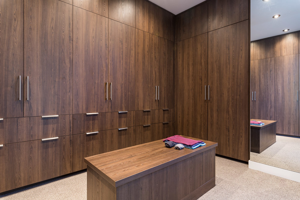 This is an example of a large contemporary gender neutral dressing room in Calgary with flat-panel cabinets, medium wood cabinets, carpet and grey floors.