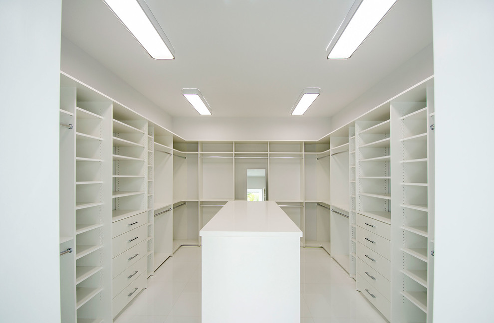 Ejemplo de vestidor minimalista extra grande con puertas de armario blancas, suelo de baldosas de porcelana y suelo blanco