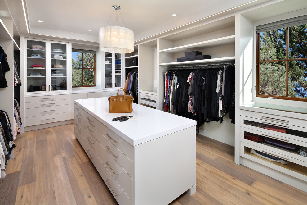 Photo of a contemporary dressing room for women in San Francisco with white cabinets, light hardwood flooring and flat-panel cabinets.