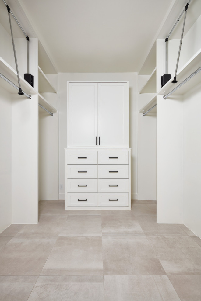 Пример оригинального дизайна: большая гардеробная комната унисекс в современном стиле с фасадами с утопленной филенкой, белыми фасадами, полом из керамической плитки, бежевым полом и сводчатым потолком