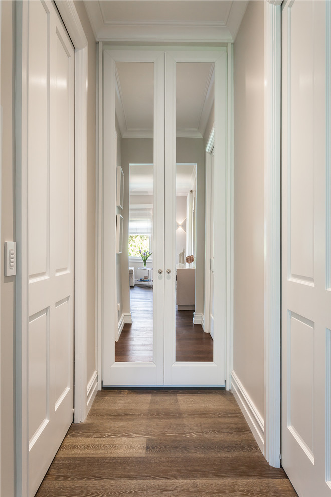 Ejemplo de armario vestidor unisex clásico grande con puertas de armario blancas, suelo de madera en tonos medios y suelo marrón