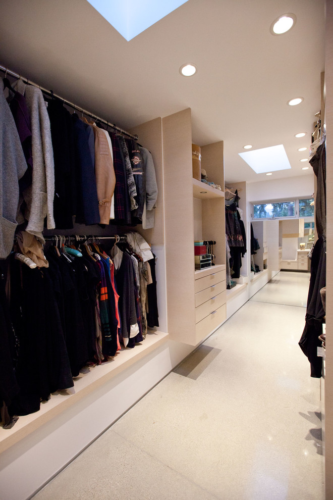 Large modern gender neutral dressing room in Vancouver with flat-panel cabinets, light wood cabinets and concrete flooring.