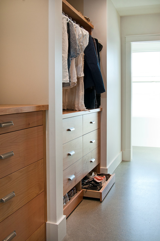 Ejemplo de armario vestidor unisex clásico renovado de tamaño medio con armarios con paneles lisos, puertas de armario de madera oscura y suelo de cemento