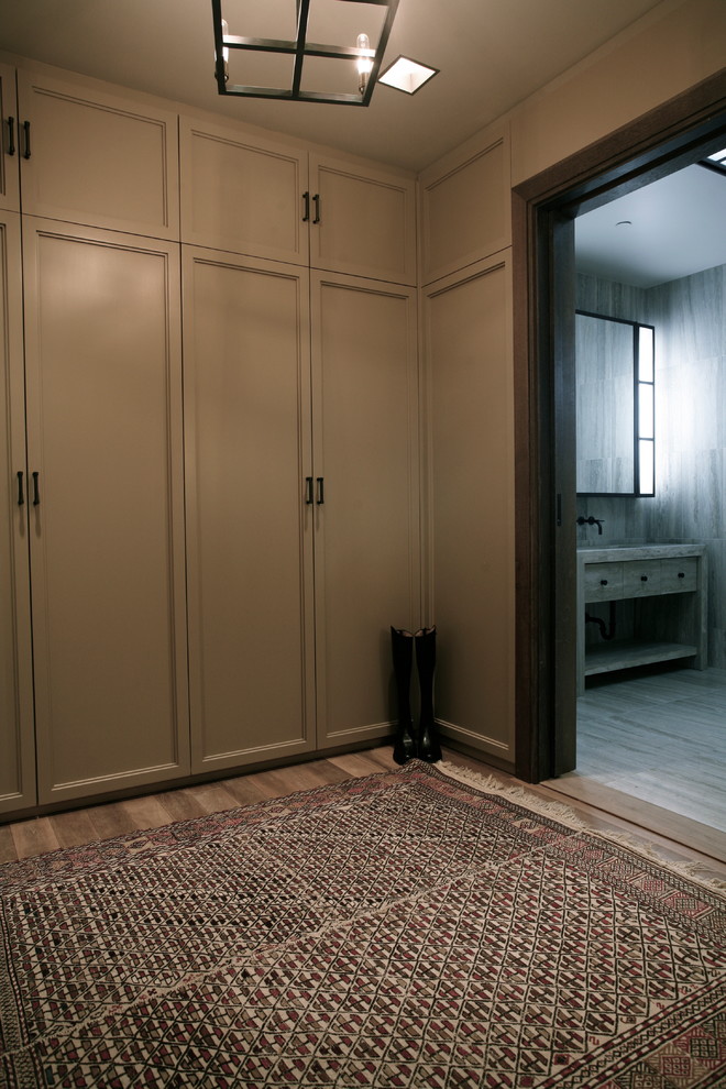 Diseño de armario vestidor unisex tradicional renovado de tamaño medio con armarios con paneles lisos, puertas de armario beige y suelo de madera en tonos medios