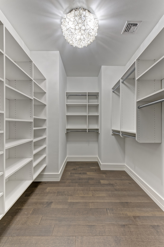 Идея дизайна: гардеробная комната среднего размера, унисекс в стиле неоклассика (современная классика) с плоскими фасадами, белыми фасадами, деревянным полом и коричневым полом