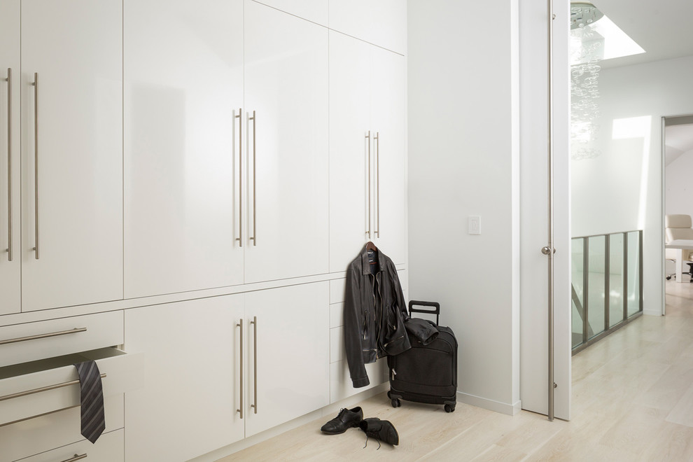 Immagine di un grande armadio o armadio a muro per uomo moderno con ante lisce, ante bianche e parquet chiaro
