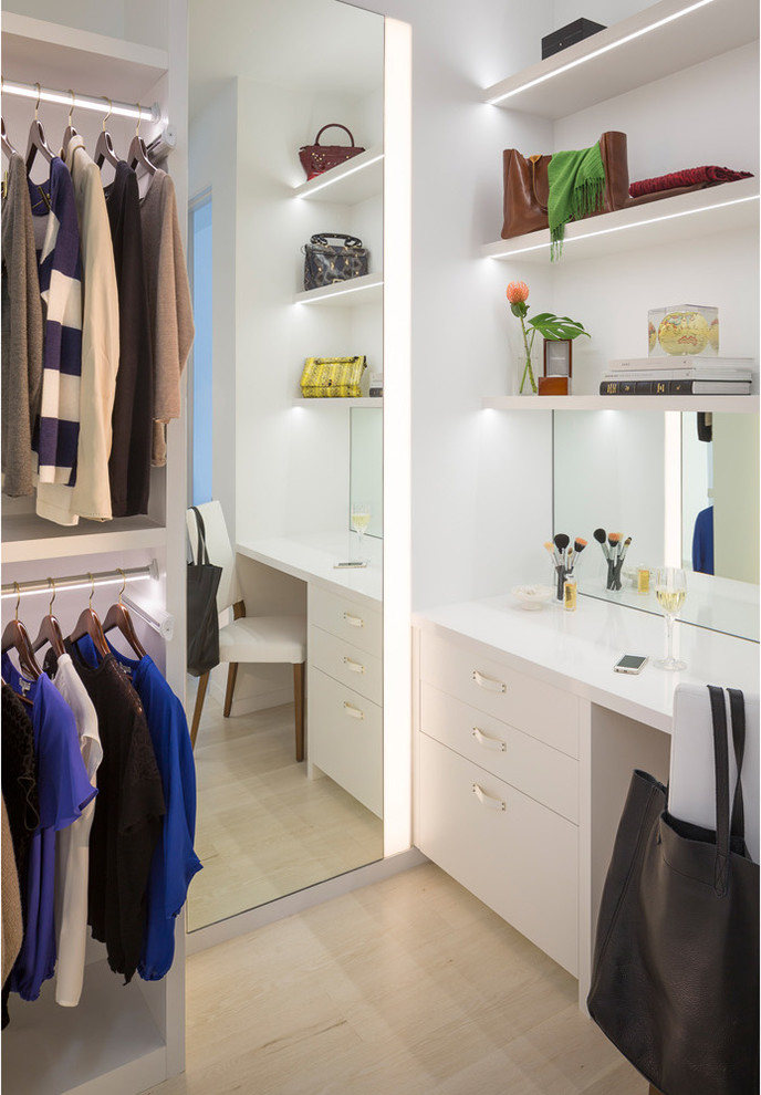 Ejemplo de armario vestidor de mujer actual grande con armarios con paneles lisos, puertas de armario blancas y suelo de madera clara