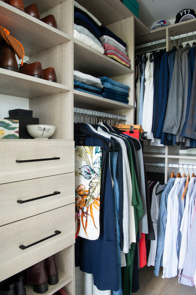 Diseño de armario vestidor actual pequeño con armarios con paneles lisos, puertas de armario de madera clara, suelo de madera clara y suelo beige
